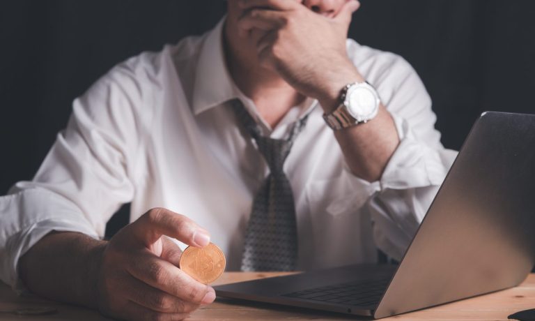 troubled man at laptop with bitcoin