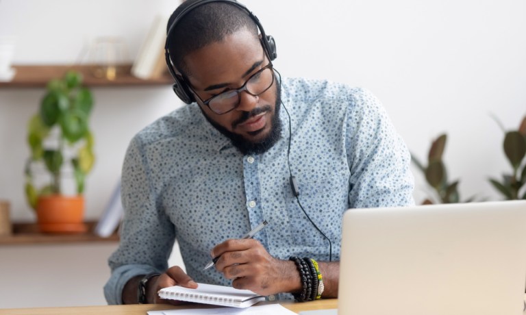 man taking notes in online class